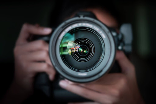 A close-up of a man holding a professional camera with a high-quality lens