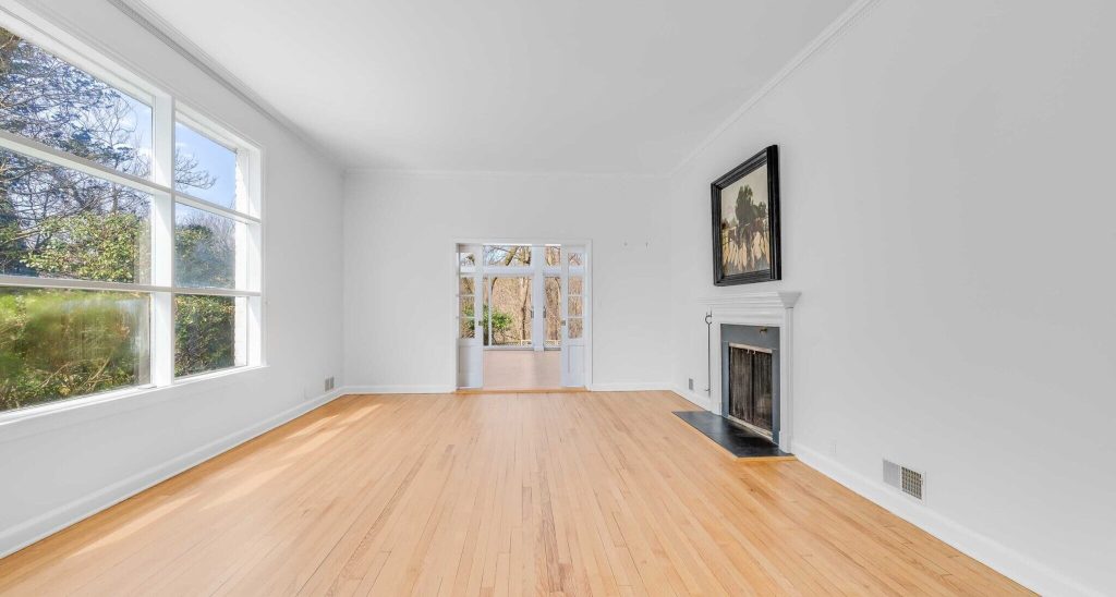 A shot of an empty room showing a fireplace and wooden floors, created by virtual staging