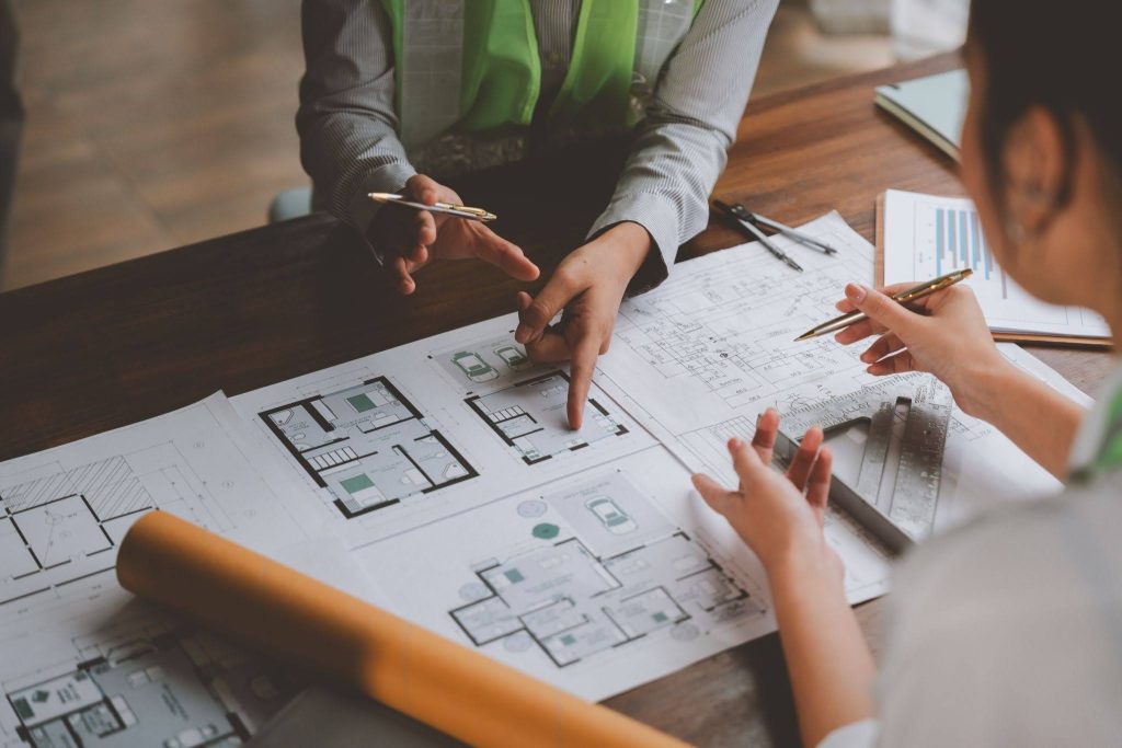 Two people discussing over floor plans in an office